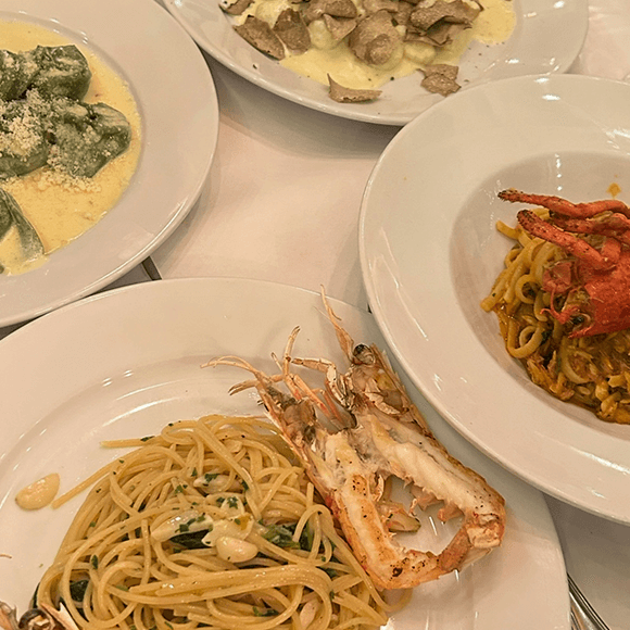 Meet You On The Mat Four plates of Italian pasta dishes, including spaghetti with shellfish, spinach ravioli, a seafood linguine, and pasta with a creamy sauce, arranged on a white tablecloth. Pilates & Dance