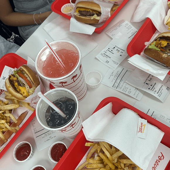 Meet You On The Mat Four trays of burgers, fries, and drinks on a white table, with receipts and small cups of ketchup visible. Pilates & Dance